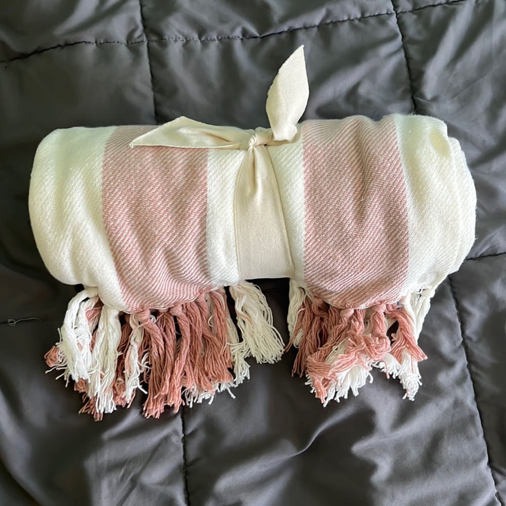 Pink & white throw blanket with tassels.